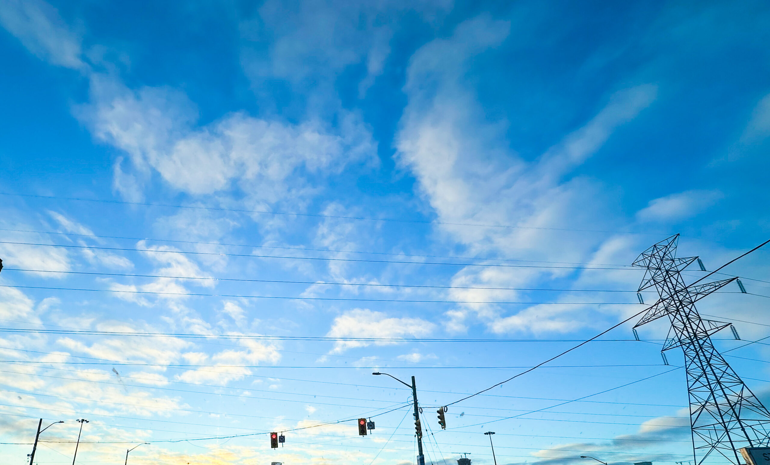 Wide angle view of the sky at a stop light intersection full of wires.